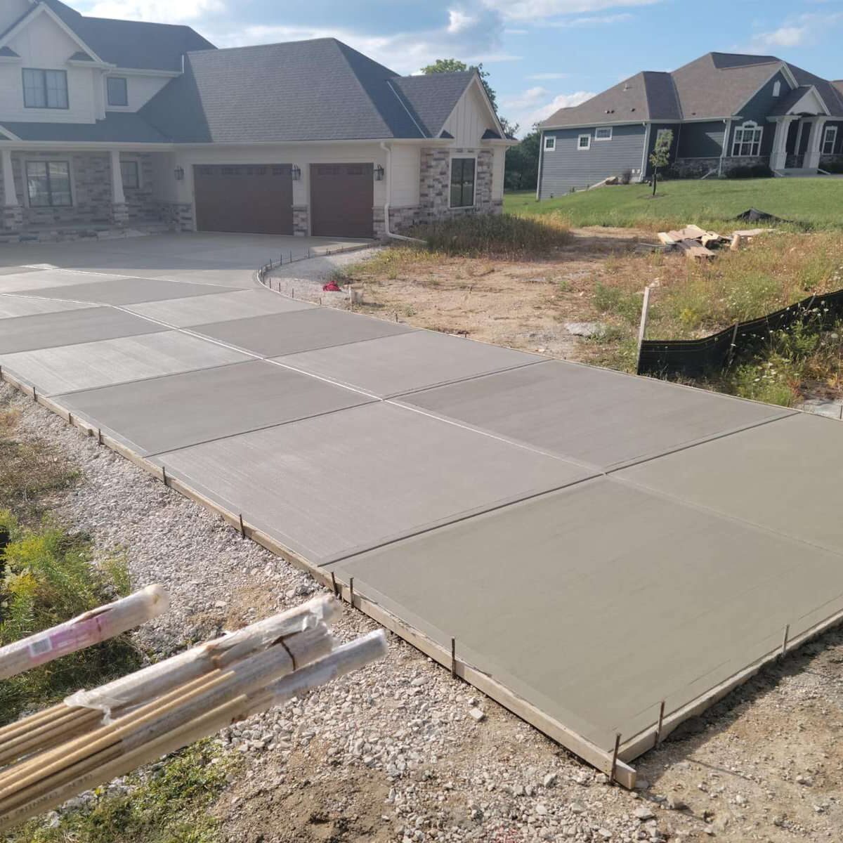 Newly poured concrete driveway leading to a residential garage in a suburban development.